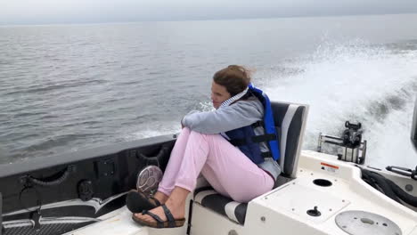 Little-girl-riding-in-back-of-motor-boat-on-lake