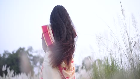 Eine-Indische-Frau-In-Saree-Mit-Schönen-Langen-Und-Lockigen-Haaren-Schwankt-Und-Bewegt-Ihr-Haar-Auf-Einem-Feld,-Zeitlupe