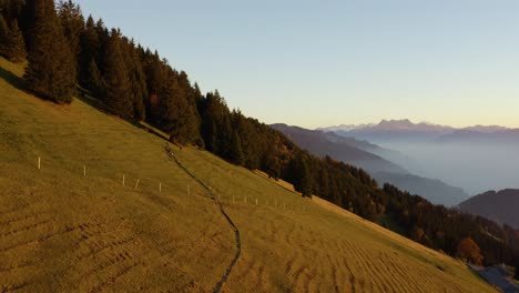 Reverse-flight-from-hikers,-revealing-alpine-landscape-and-Lake-Léman-at-sunset-with-autumn-colors---Switzerland