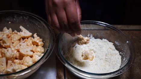 Person-dropping-cauliflower-with-sauce-into-flour-for-breading,-SLOW-MOTION
