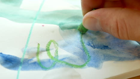 Child-scribbling-with-wax-pastel-on-messy-art-paper