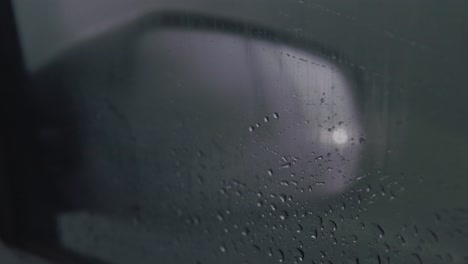 View-of-car-side-mirror-from-inside-the-car,-rainy-fog-night-ride