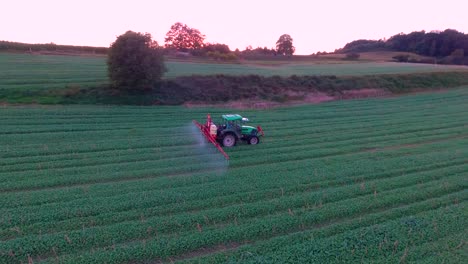 Close-Up-Aerial-View-of-Farming-Tractor-Spraying-at-Sunset