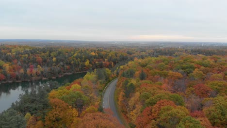 Aerial-footage-over-Pink-Lake-in-Gatineau-Quebec-going-over-the-lookout-and-parking-lot-at-the-road-with-a-biker