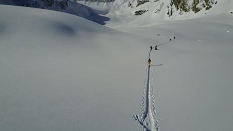 Drohne-Steigt-Vertikal-Auf,-Während-Backcountry-Skifahrer-Den-Skintrack-Hinaufsteigen