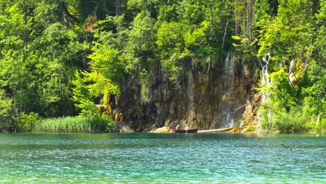 Couple-resting-on-small-boat-next-to-waterfall-in-Plitvice-National-Lake-Park