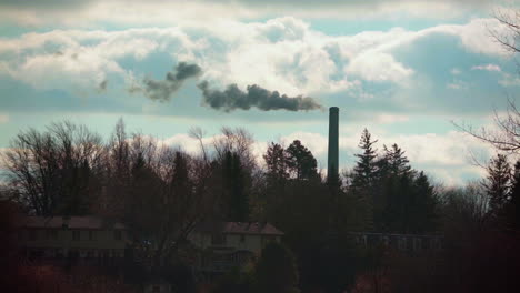 Wide-angle-of-a-smoke-stack-spewing-dark-thick-smoke-into-the-sky-on-a-beautiful-day