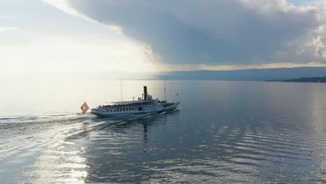 Following-and-closing-in-on-Belle-Epoque-steam-boat-on-Lake-Léman---Switzerland-Sunset,-mirror-like-water-and-storm-clouds-in-the-background