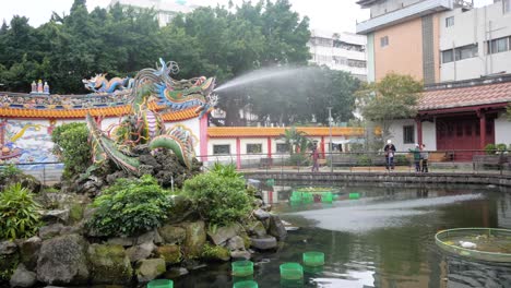 Slow-motion-shot-of-dragon-fountain-in-lake-at-Baoan-Temple-Garden-in-Taipei,-Taiwan