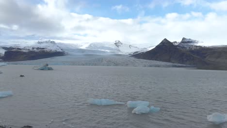 Toma-Aérea-Lenta-Desde-Una-Plataforma-Rodante-De-Una-Laguna-Glacial-Con-Icebergs-Flotantes