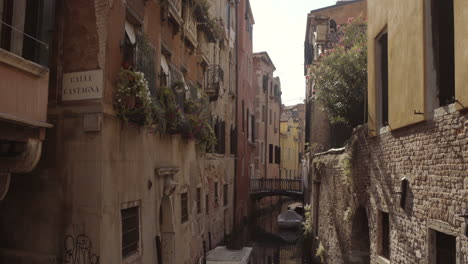 Wide-tilt-up-shot-of-historic-water-canal-street-Cale-Castagna-with-brick-wall,-Venice,-Italy
