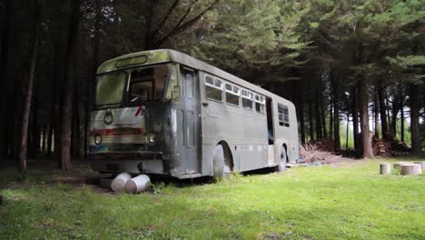 Wide-shot-of-an-abandoned-old-bus-sitting-near-a-forest