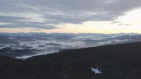 Luftdrohnenaufnahme-Einer-Atemberaubenden-Winterlandschaft-Mit-Einer-Kleinen-Stadt-Im-Hintergrund