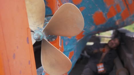 Greek-fisherman-repairs-wooden-boat-slow-motion-focus-on-propeller