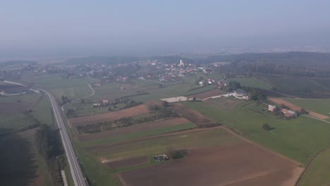 High-altitude-aerial-view-of-farmland-near-the-village-of-Cresnjevec-in-the-countryside-of-Slovenia-on-a-foggy-morning
