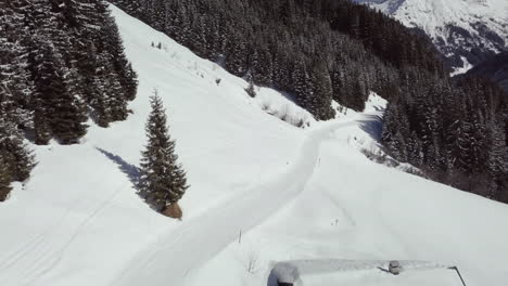 Aerial-drone-shot-of-snowy-landscape,-pathway-in-skiing-area-of-Kleinwalsertal-in-the-alps,-Austria