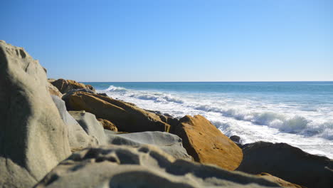 Eine-Meereswelle-Kracht-Und-Rutscht-In-Zeitlupe-Gegen-Einen-Felsigen-Kalifornischen-Strand-Nach-Rechts