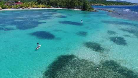 Luftaufnahme-Von-Menschen,-Die-In-Der-Nähe-Des-Strandes-Eines-Resorts-Am-Honduranischen-Karibischen-Meer-Paddeln