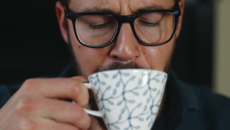 Male-face-hesitant-to-taste-coffee-cup-shaking-his-head-close-up
