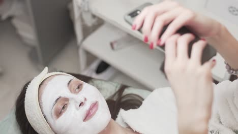 Girl-smiling-and-taking-photos-of-herself-with-a-face-mask-applied
