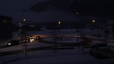 Tag-zu-Nacht-Zeitraffer-Von-Autos,-Die-Bei-Starkem-Schneefall-In-Der-Schweiz-Um-Einen-Kreisverkehr-Fahren