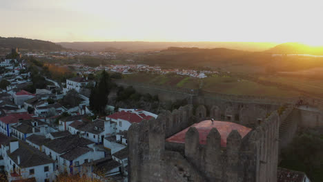 An-aerial-flyover-of-a-Castle-in-Óbidos,-Portugal-at-golden-hour