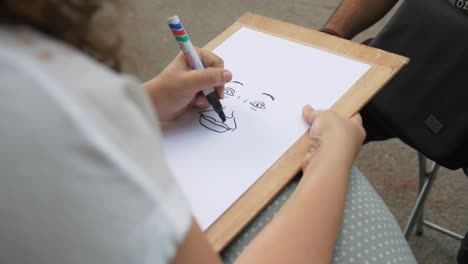 Girl-drawing-face-of-a-man-in-the-park