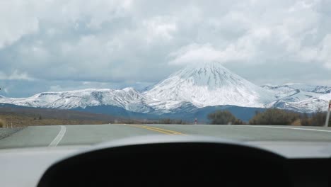 Conduciendo-Cuesta-Arriba-Para-Revelar-Una-Gran-Montaña-Cubierta-De-Nieve