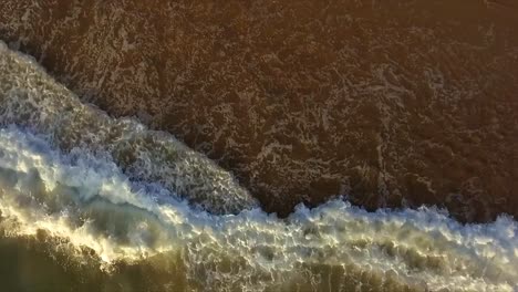 Aerial-drone-shot-looking-straight-down-at-the-surf-rolling-up-the-beach-at-Coffs-Harbour