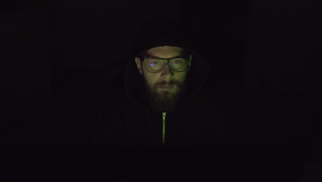Hacker-with-uncovered-face-is-working-on-the-pc-in-the-dark-room
