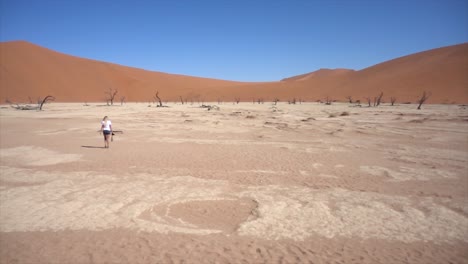 Slomo-Wide-of-Young-Millenial-Woman-in-Deadvlei-surrounded-by-Dead-Trees-against-a-Blue-Sky