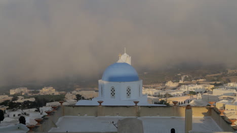 Time-Lapse-shot-overlooking-a-cycladic-village,-with-a-blue-church-dome-dominant