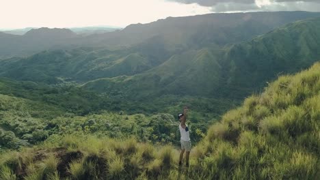 Drone-footage-of-a-young-man-taking-a-selfie-with-landscape-and-mountains-from-behind