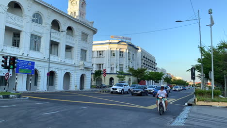 Zeitrafferaufnahmen-Einer-Straße-In-Penang,-Malaysia-Mit-Vielen-Autos-Und-Motorrädern-Und-Einem-Weißen-Gebäude-Im-Hintergrund