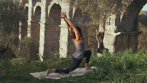 Eine-Fitte-Yogalehrerin-Führt-Yoga-Pose-In-Der-Natur-Am-Antiken-Aquädukt-Durch