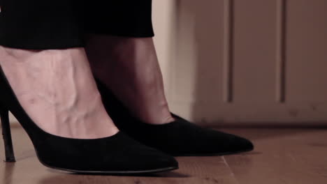 Primer-Plano-De-Una-Mujer-Caminando-Con-Zapatos-Negros-De-Tacones-Altos-En-Un-Piso-De-Madera