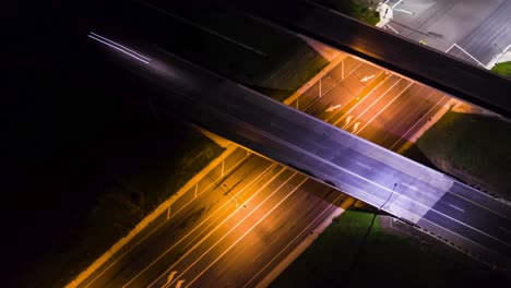 Hyper-Lapse-Drone-of-intersection-at-night-while-cars-drive-onto-the-overpass