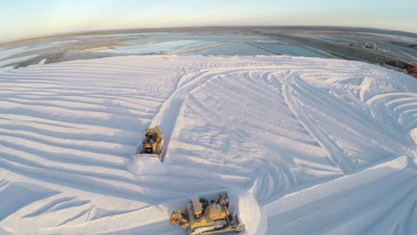 Aerial-drone-shot-of-tractors-working-on-a-large-salt-deposit-in-the-salt-flats-by-solar-evaporation-in-Guerrero-Negro,-Ojo-de-Liebre-lagoon,-Biosphere-Reserve-of-El-Vizcaino,-Baja-California-Sur