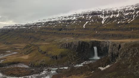Wasserfall-Ergießt-Sich-In-Ein-üppiges,-Schneebedecktes-Tal-In-Island