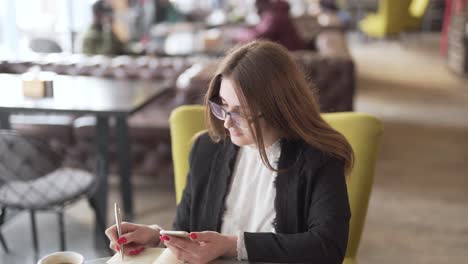 Woman-taking-notes-in-a-coffee-shop-before-receiving-phone-call