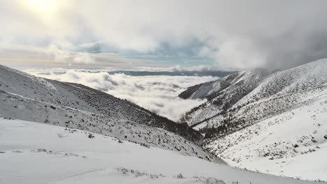 Nubes-Rodando-Sobre-El-Valle-Cubierto-De-Nieve-Entre-Altos-Picos-Alpinos-En-Tatras,-Eslovaquia