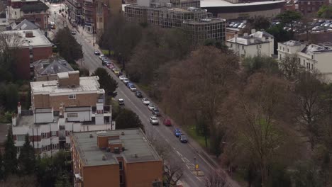Aerial-view-tracking-an-unrecognizable-4X4-SUV-on-London-streets,-descending-aerial-shot