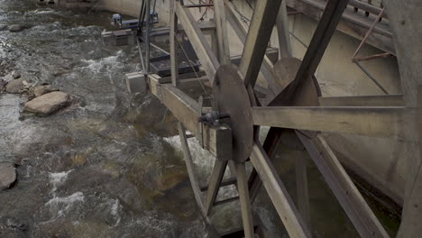 Tilt-up-shot-with-some-movement-of-an-old-antique-water-wheel-on-a-river-in-a-tourist-town-in-Colorado