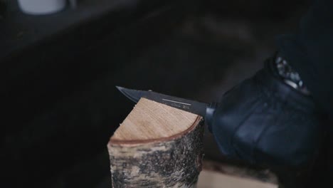 man-cutting-firewood-with-a-knife-in-winter-in-Lemmenlaakso,-Finland-shot-in120fps