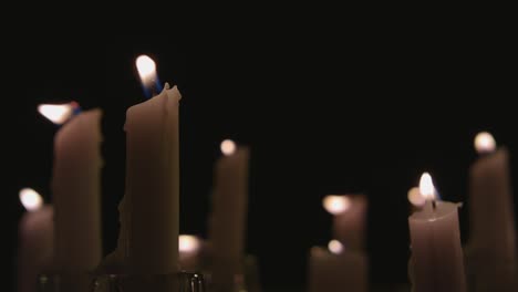 An-extreme-close-up-of-white-candles-lit-with-a-black-background