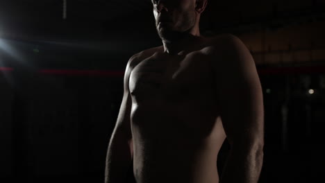 Mediums-handheld-shot-on-a-young-MMA-fighter's-torso-as-he-moves-back-and-forth-in-a-dark-lit-ring