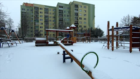 Snow-is-falling-in-a-small-playground-in-a-city's-suburbs