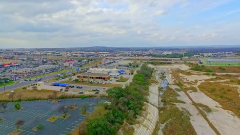 Drone-footage-of-the-flood-plain-with-shops,-car-parks-and-road-or-highway-of-to-the-sides-moving-backwards