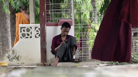burmese-man-sitting-on-the-floor-outside-under-trees
