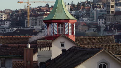 Kleiner-Roter-Turm-Zwischen-Rauchenden-Schornsteinen,-Vorbeifliegende-Vögel